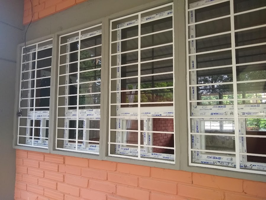 Ventanas en PVC con reja de seguridad en fachada de ladrillo – Clínica – ventanas hospitalarias en PVC