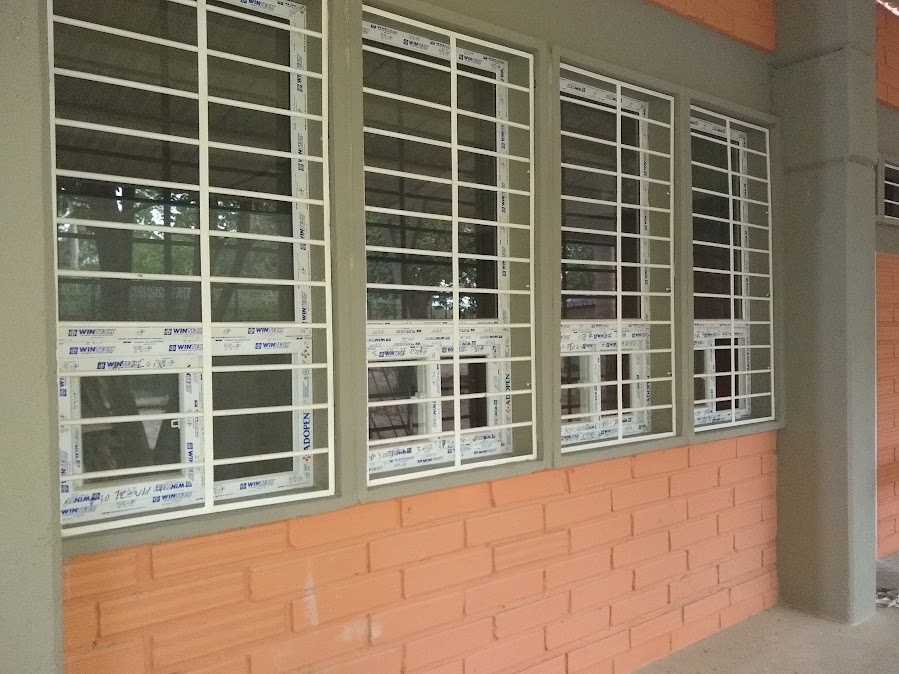 Ventanas en PVC con reja de seguridad en fachada de ladrillo – Clínica – ventanas hospitalarias en PVC